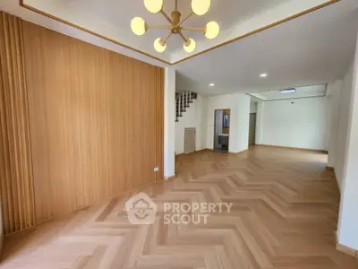 Spacious modern living room with elegant wooden flooring and stylish lighting fixture.