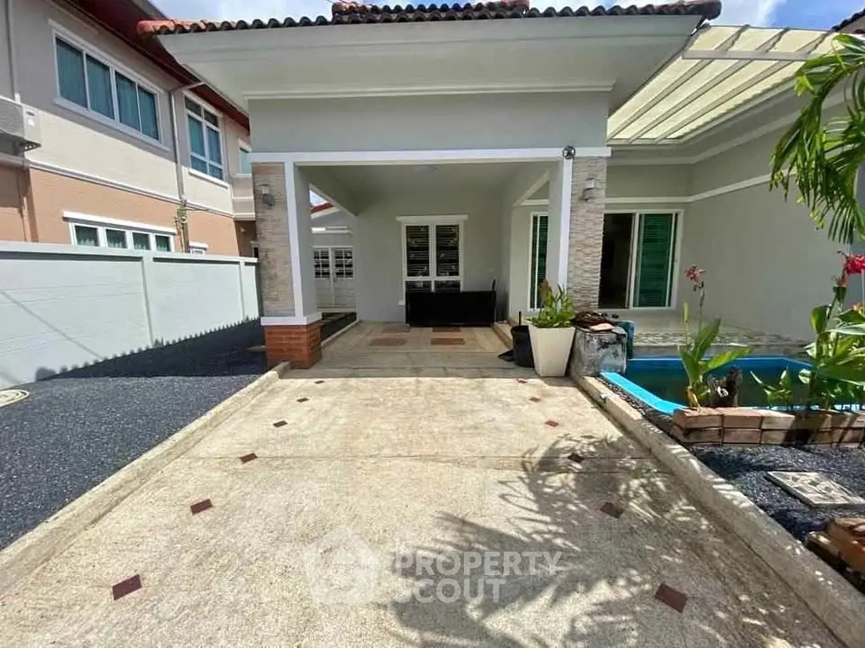 Charming single-story home with spacious driveway and cozy outdoor seating area.