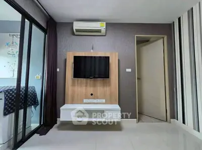 Modern living room with wall-mounted TV and air conditioning in stylish apartment.