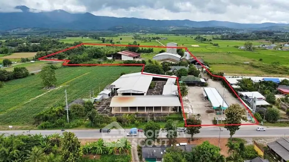 Expansive agricultural property with multiple buildings and lush green fields, ideal for farming or development.