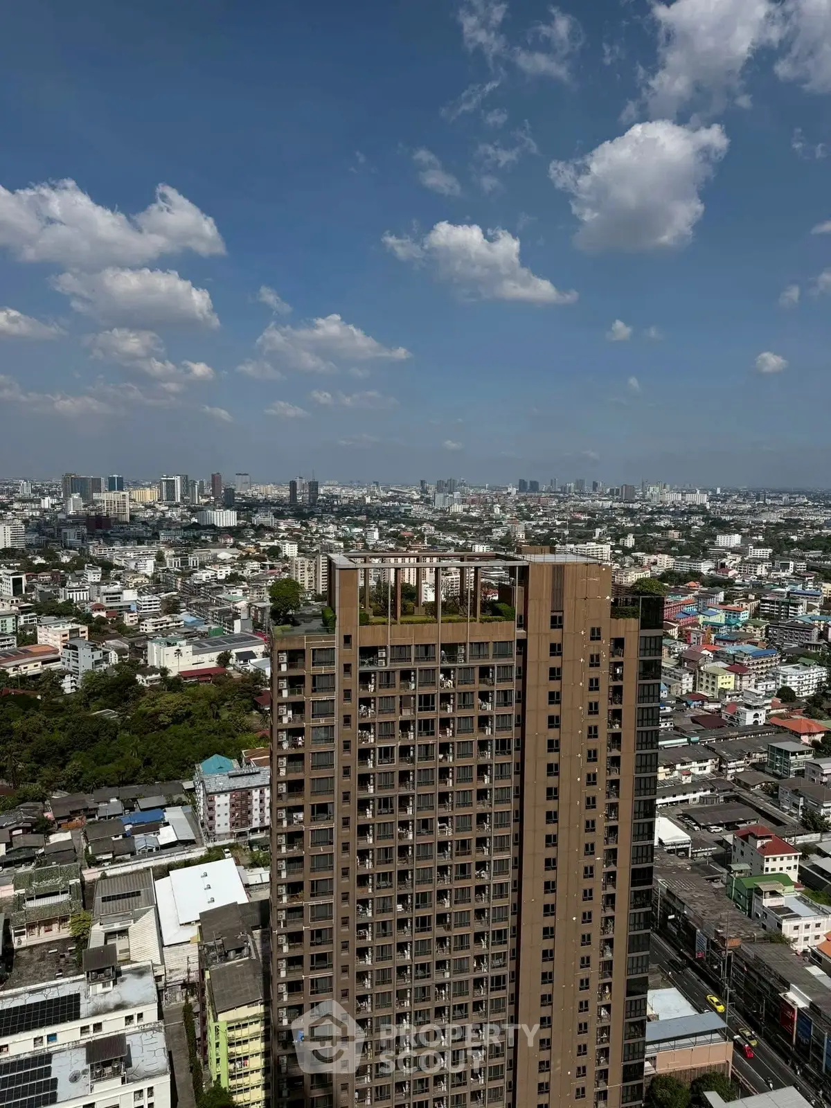 Stunning aerial view of a high-rise building with cityscape backdrop under a clear blue sky.