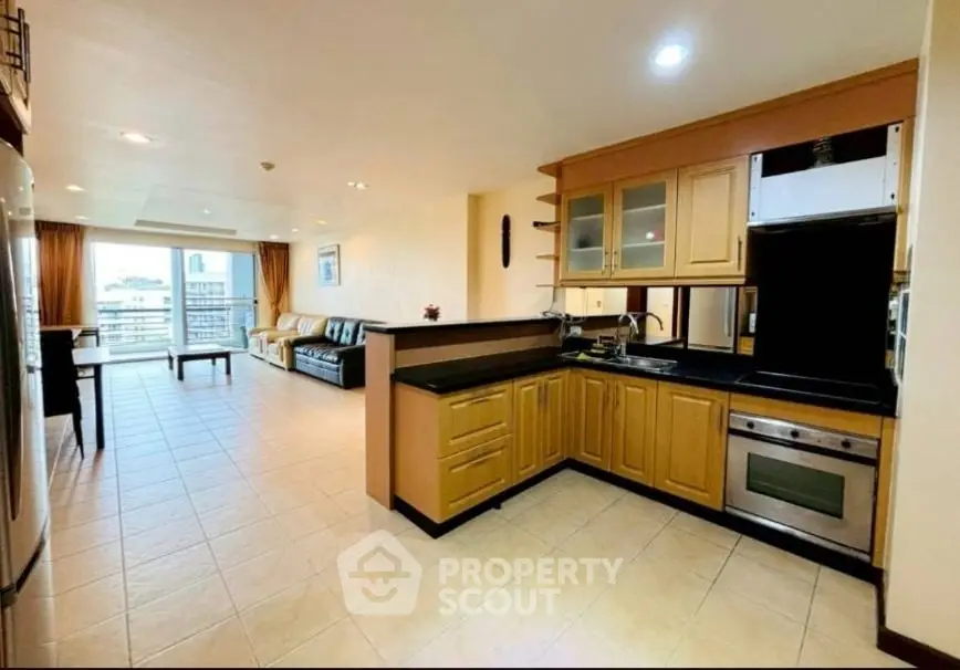 Spacious open-plan living room with modern kitchen and balcony view.