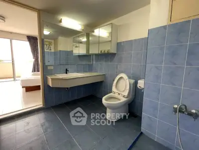 Spacious bathroom with blue tiles and modern fixtures in a bright apartment.