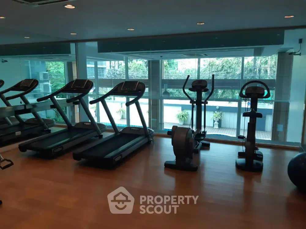 Modern gym with state-of-the-art equipment and pool view in luxury residential building.