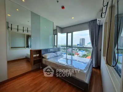 Modern bedroom with large windows offering stunning city views, featuring a comfortable bed and sleek wooden flooring.