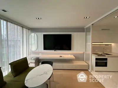 Modern living room with sleek TV setup and adjacent kitchen area in luxury apartment.