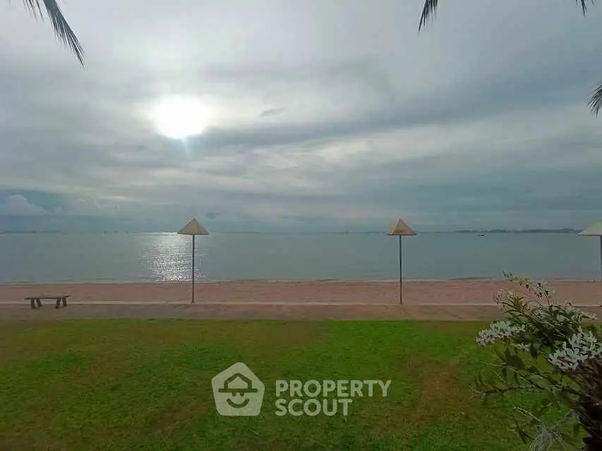 Scenic beachfront view with lush green lawn and serene ocean horizon.