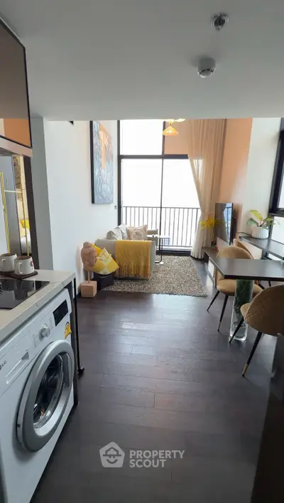 Modern living room with balcony view, featuring stylish decor and a washing machine in an open layout.
