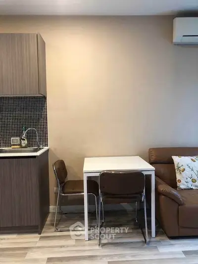 Modern compact kitchen and dining area with sleek cabinetry and cozy seating.