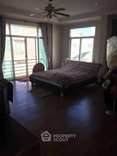 Spacious bedroom with large windows and wooden flooring, offering ample natural light and a cozy atmosphere.