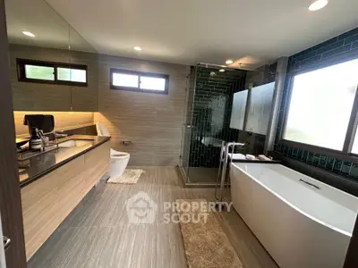 Luxurious modern bathroom with freestanding bathtub and glass shower enclosure.