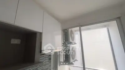 Modern kitchen with sleek cabinets and large window showcasing air conditioning units.