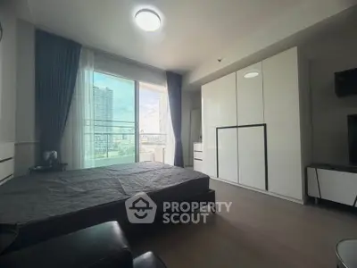 Modern bedroom with large window and city view, featuring sleek white wardrobe and contemporary furnishings.