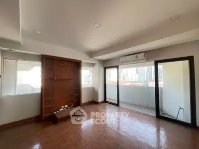 Spacious living room with large windows and balcony offering city views