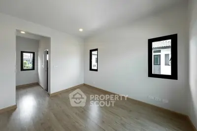 Spacious empty room with wooden flooring and large windows in modern home