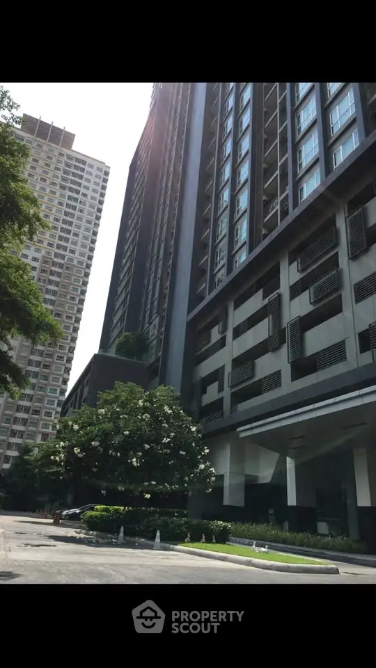 Modern high-rise building exterior with lush greenery and sleek architectural design.