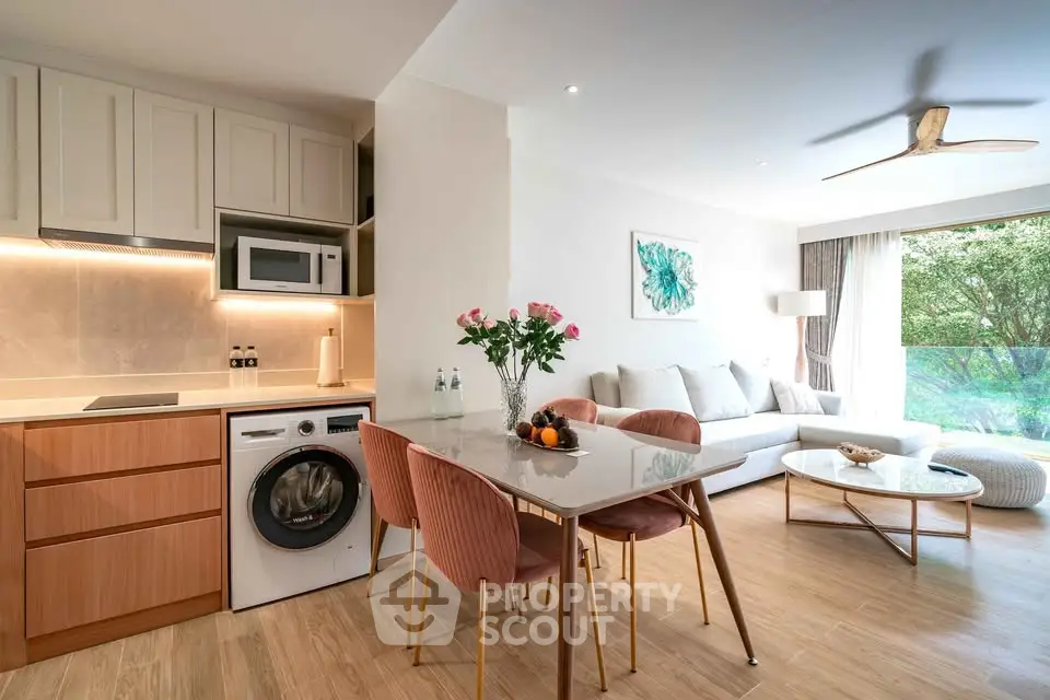 Modern open-plan living room with stylish kitchen and dining area, featuring natural light and elegant decor.