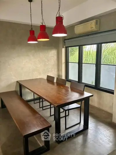 Modern dining area with industrial design, featuring wooden table, metal chairs, and red pendant lights.