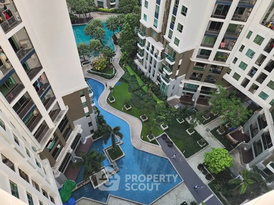 Stunning aerial view of modern residential complex with lush gardens and inviting pool area.