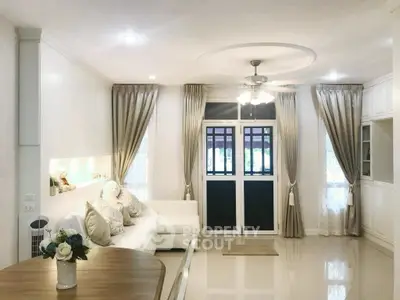 Elegant living room with plush sofa, stylish curtains, and ceiling fan in a cozy home setting.