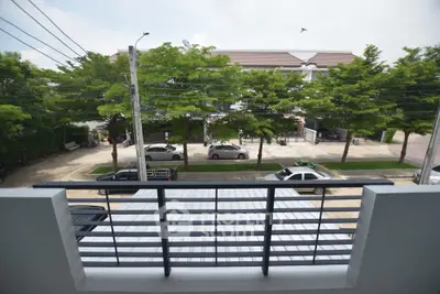 Charming balcony view overlooking serene neighborhood street with lush greenery and parked cars.