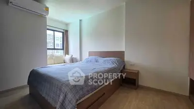 Cozy bedroom with modern furnishings and large window offering natural light.