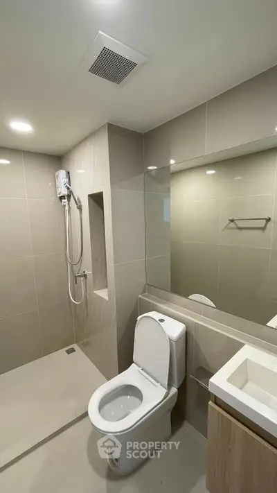 Modern bathroom with sleek design, featuring a shower and toilet in a neutral color palette.