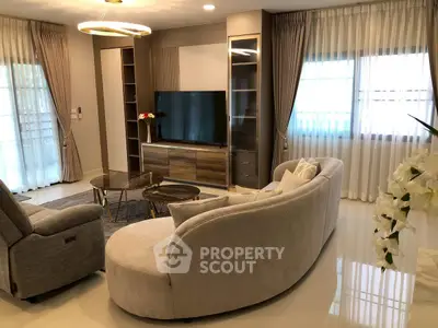 Luxurious living room with elegant furniture and modern decor, featuring a large TV and stylish lighting.
