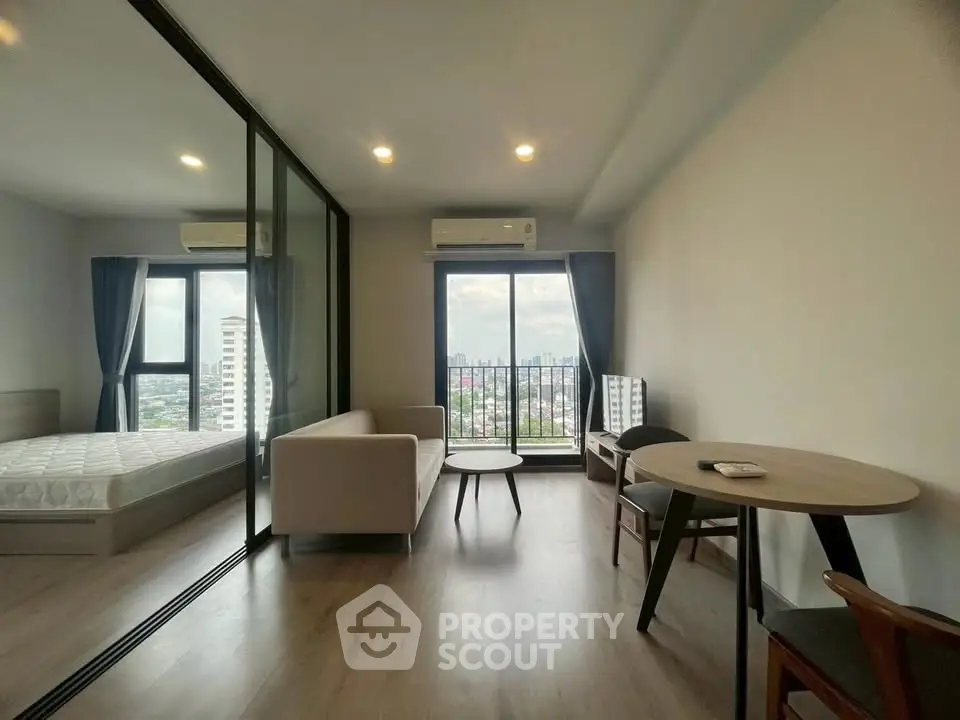 Modern apartment with city view, featuring cozy living area and bedroom with large windows.