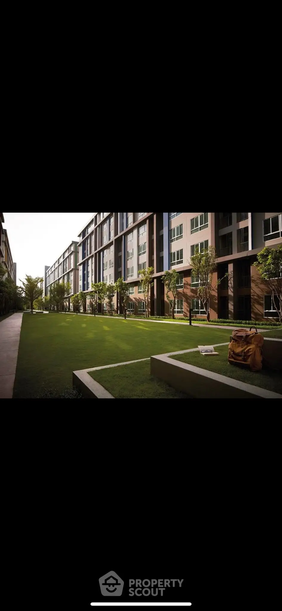 Modern apartment complex with lush green courtyard and contemporary architecture.