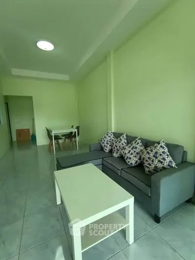 Spacious living room with modern gray sofa and dining area, perfect for relaxation and entertaining.