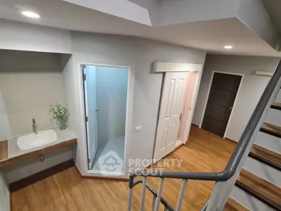 Modern interior with wooden flooring, staircase, and bathroom access in a stylish apartment.