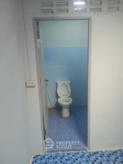 Compact bathroom with blue tiles and basic toilet setup