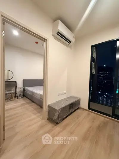 Modern bedroom with air conditioning and city view, featuring sleek wooden flooring and contemporary design.