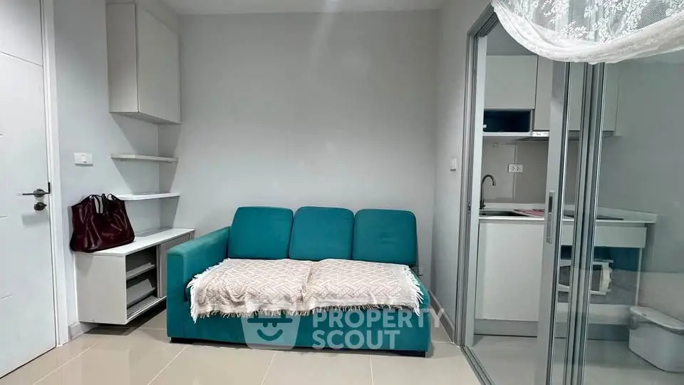 Modern living room with teal sofa and adjacent compact kitchen in a cozy apartment.