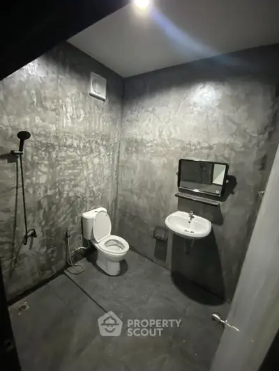 Modern industrial-style bathroom with concrete walls and minimalist fixtures.