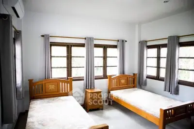 Bright bedroom with twin wooden beds and large windows for natural light.