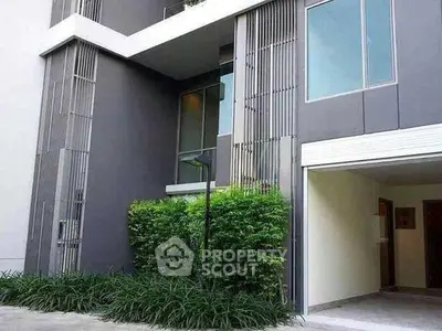 Modern townhouse exterior with sleek design and lush greenery