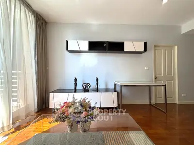 Modern living room with stylish furniture and natural light, featuring a sleek cabinet and elegant decor.