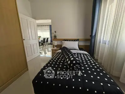 Cozy bedroom with stylish black and white bedding, natural light, and modern decor.