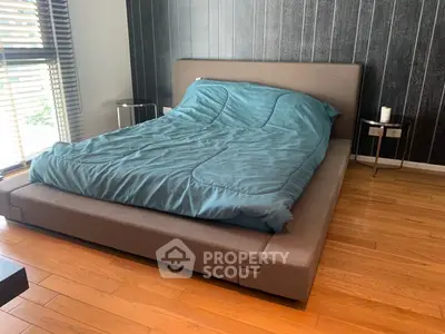 Modern bedroom with stylish bed and wooden flooring, featuring sleek design and natural light.