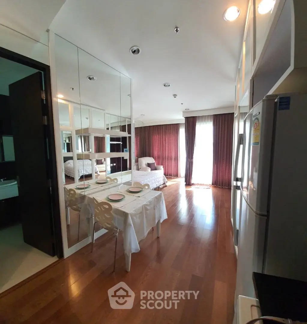 Chic modern apartment with mirrored walls and elegant dining area, featuring hardwood floors and natural light.