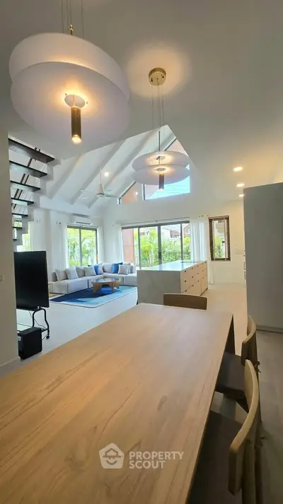 Spacious modern living room with high ceilings and large windows offering natural light and garden views.