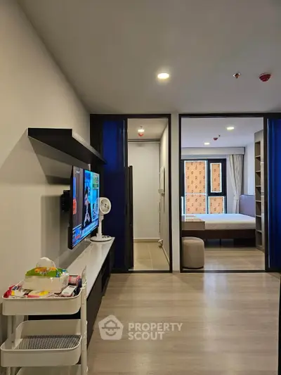 Modern apartment interior with open living area and bedroom, featuring sleek design and contemporary furnishings.