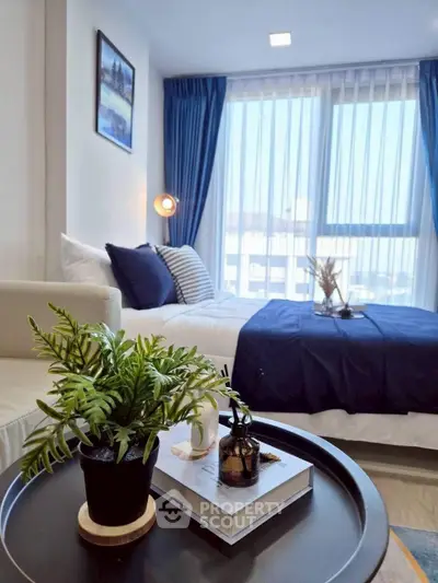 Modern bedroom with stylish decor and large window offering natural light.