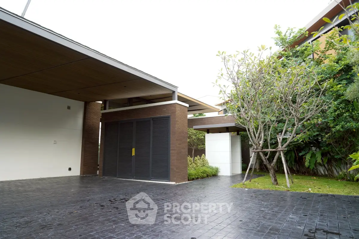 Modern home exterior with sleek design and lush greenery, featuring a spacious driveway and contemporary architecture.