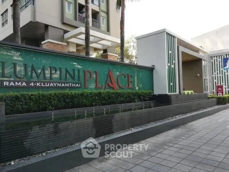 Modern residential building entrance with stylish signage and landscaped walkway.