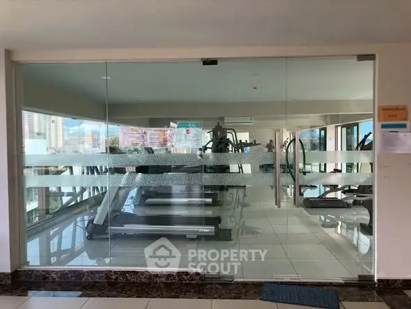 Modern gym with glass doors and city view in luxury apartment building