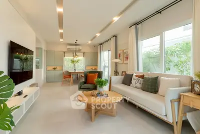 Modern living room with stylish decor and open kitchen layout, featuring large windows and cozy seating.