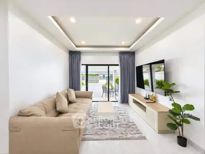 Modern living room with beige sofa, sleek TV unit, and large windows opening to a patio.